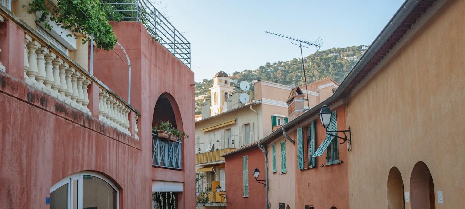 Gepflasterte Gasse mit pastellfarbenen Fassaden in einem Dorf der Côte d'Azur