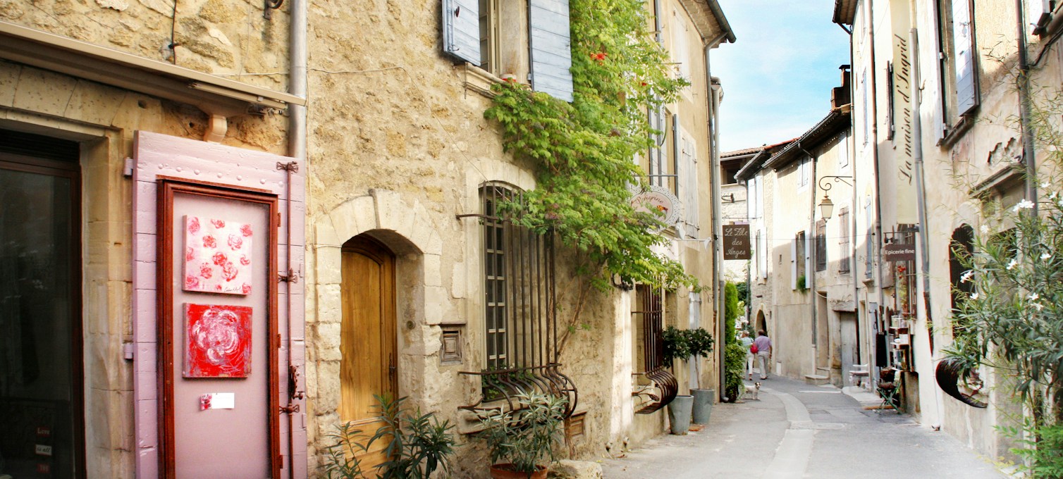 Gasse eines Dorfes in der Provence, Steinfassaden und pastellfarbene Fensterläden