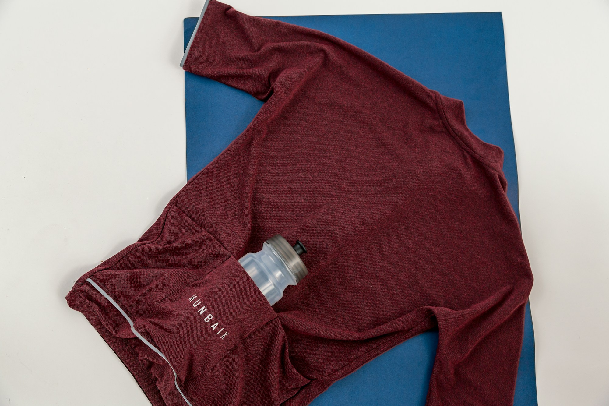 Maillot technique et gourde posés sur un tapis bleu