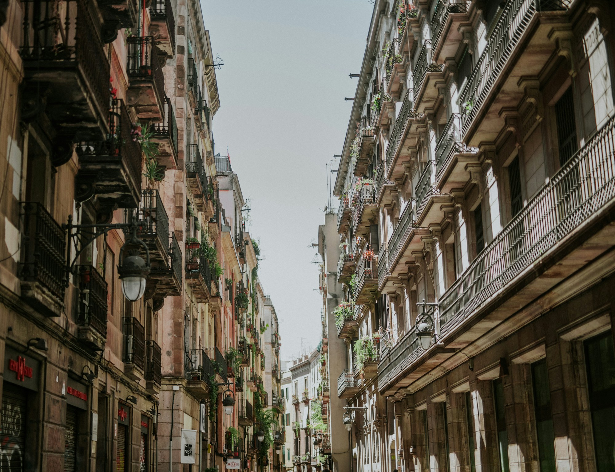 Calle luminosa de Barcelona con edificios y balcones de hierro forjado