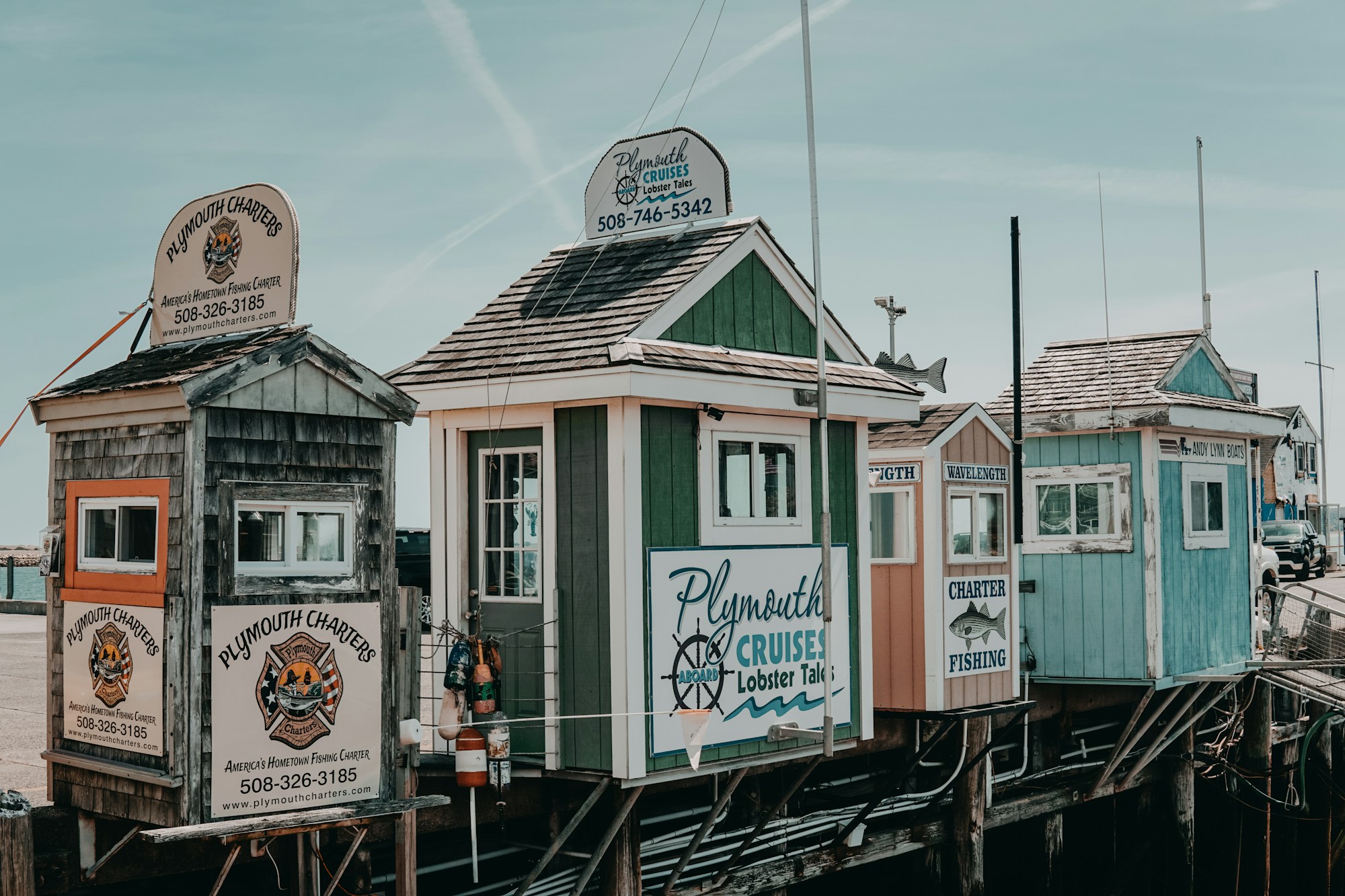 Kiosques colorés « Plymouth Cruises » et « Plymouth Charters » sur pilotis, sur le quai de Plymouth