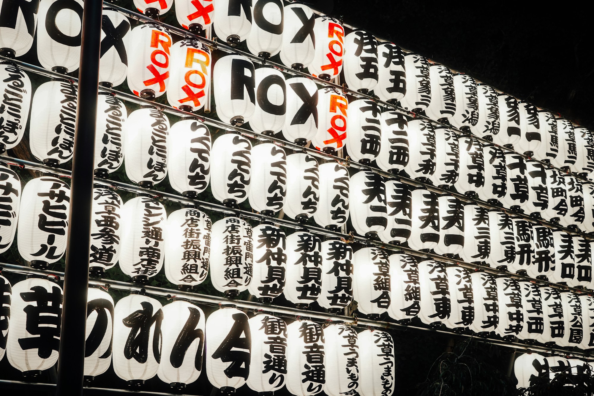 Rows of white lanterns covered in Japanese characters in front of Sensō-ji temple, in Asakusa