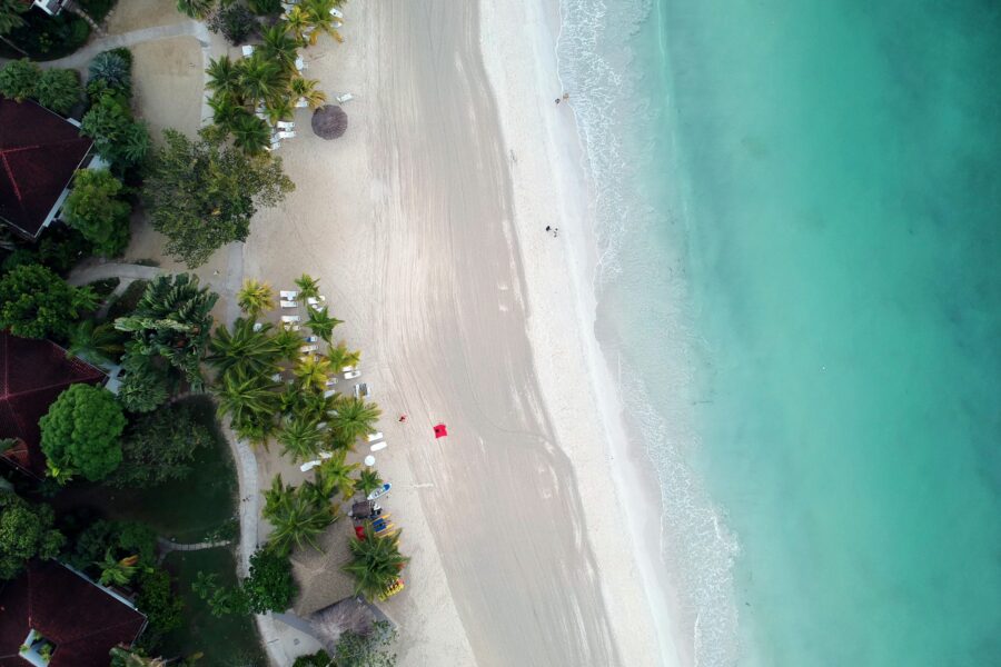 Vue aérienne de la plage de sable blanc de Negril, bordée de palmiers, face à une mer turquoise