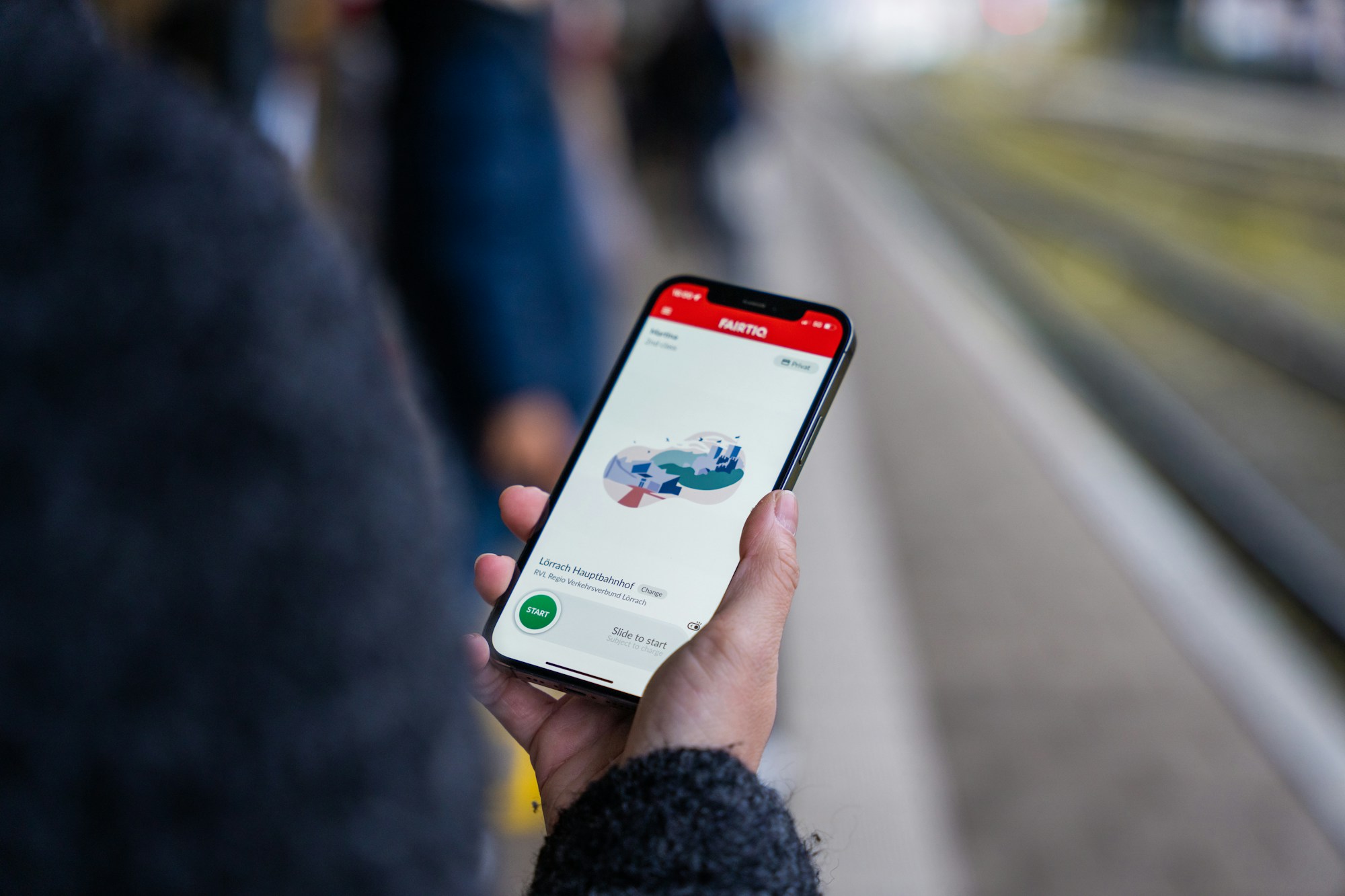 Person holding a smartphone showing a transport app on a platform