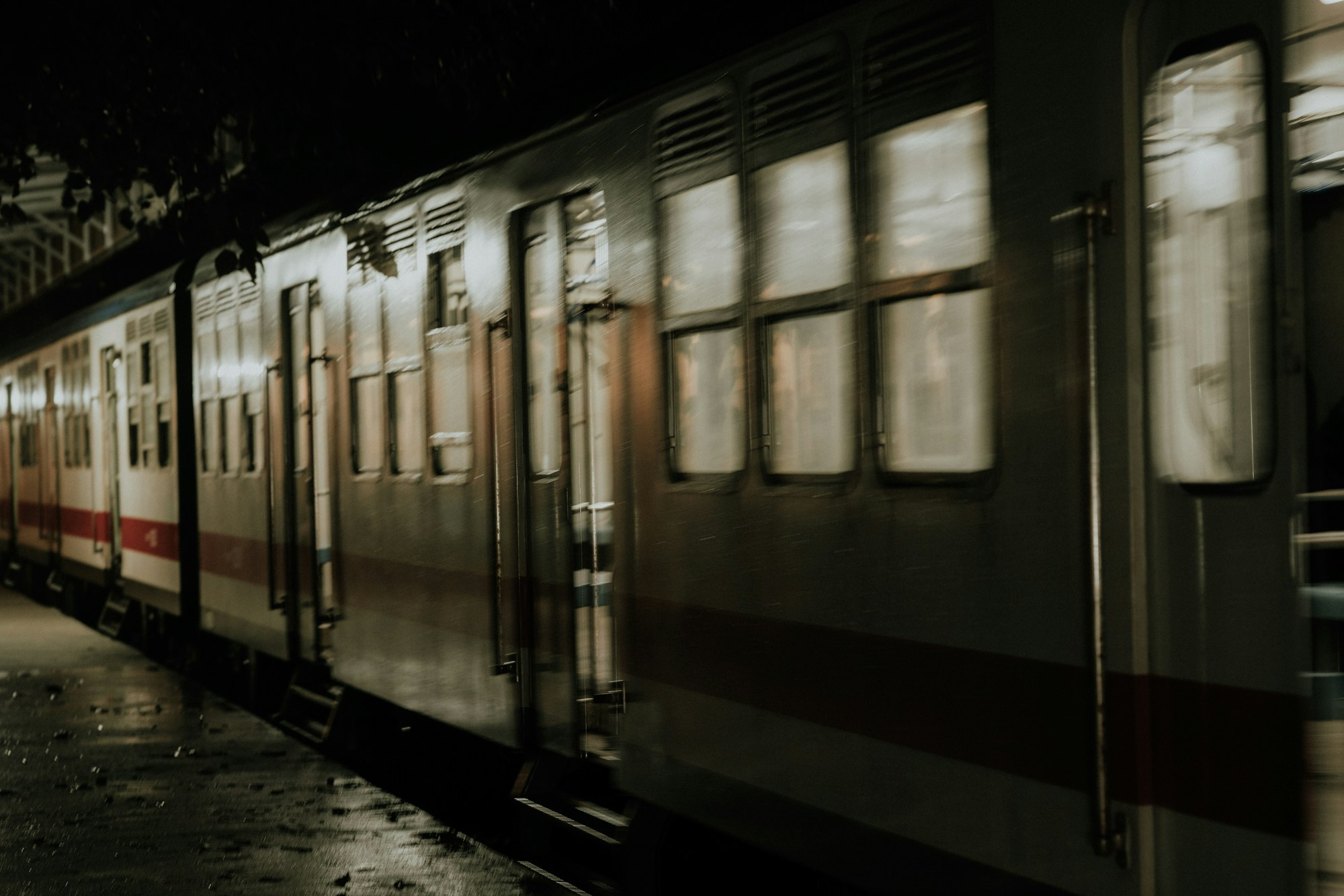 Train moving through a station at night, with lit windows