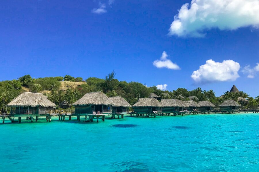 Bungalows sur pilotis aux toits de chaume face au lagon turquoise de Bora Bora, en Polynésie française