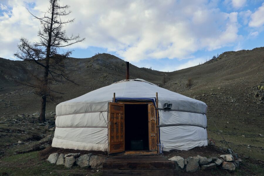 Une yourte mongole au pied d'un versant de steppe, sous un ciel de nuages