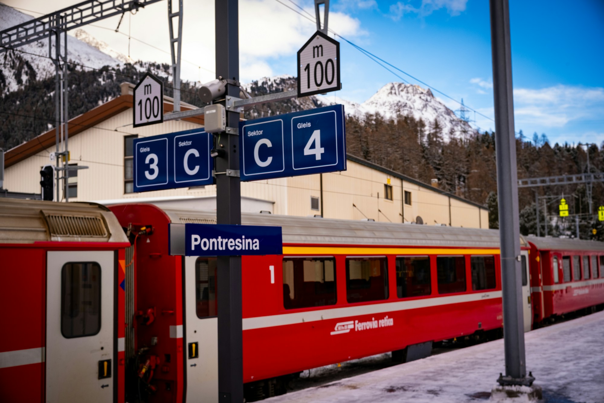 Red regional train at a platform in a Swiss mountain station