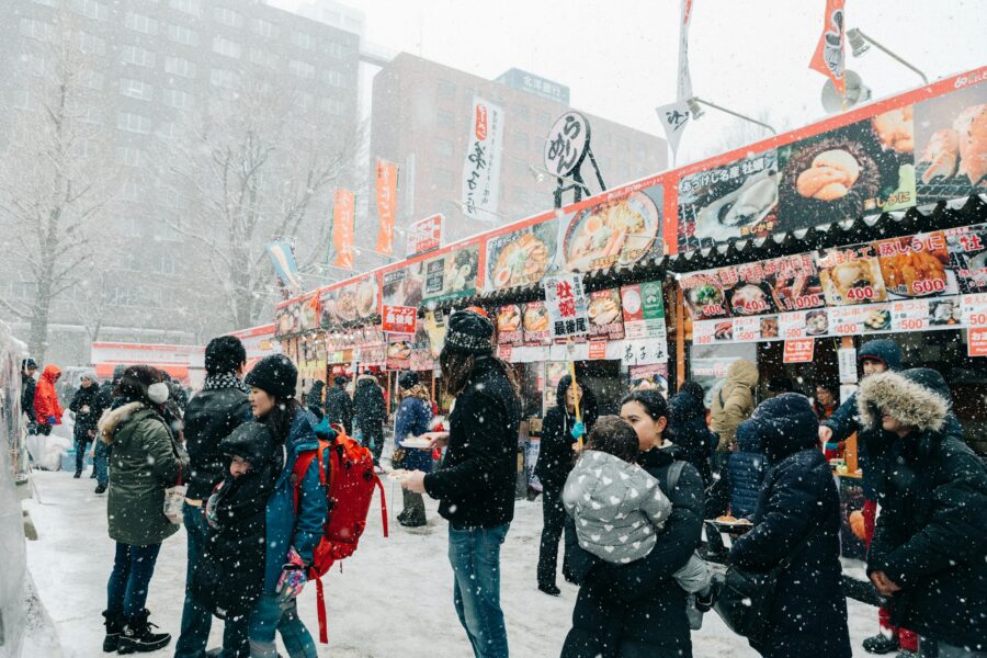 Passants sous la neige devant les stands de nourriture du festival de la neige de Sapporo
