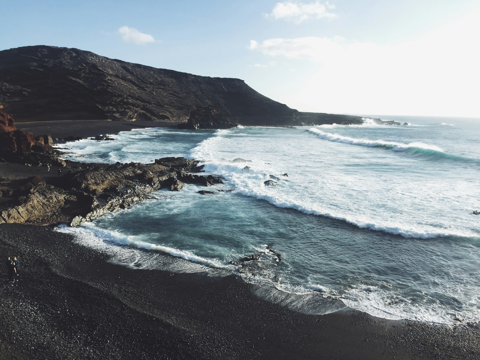 Black volcanic sand beach and coastline of Lanzarote facing a blue sea
