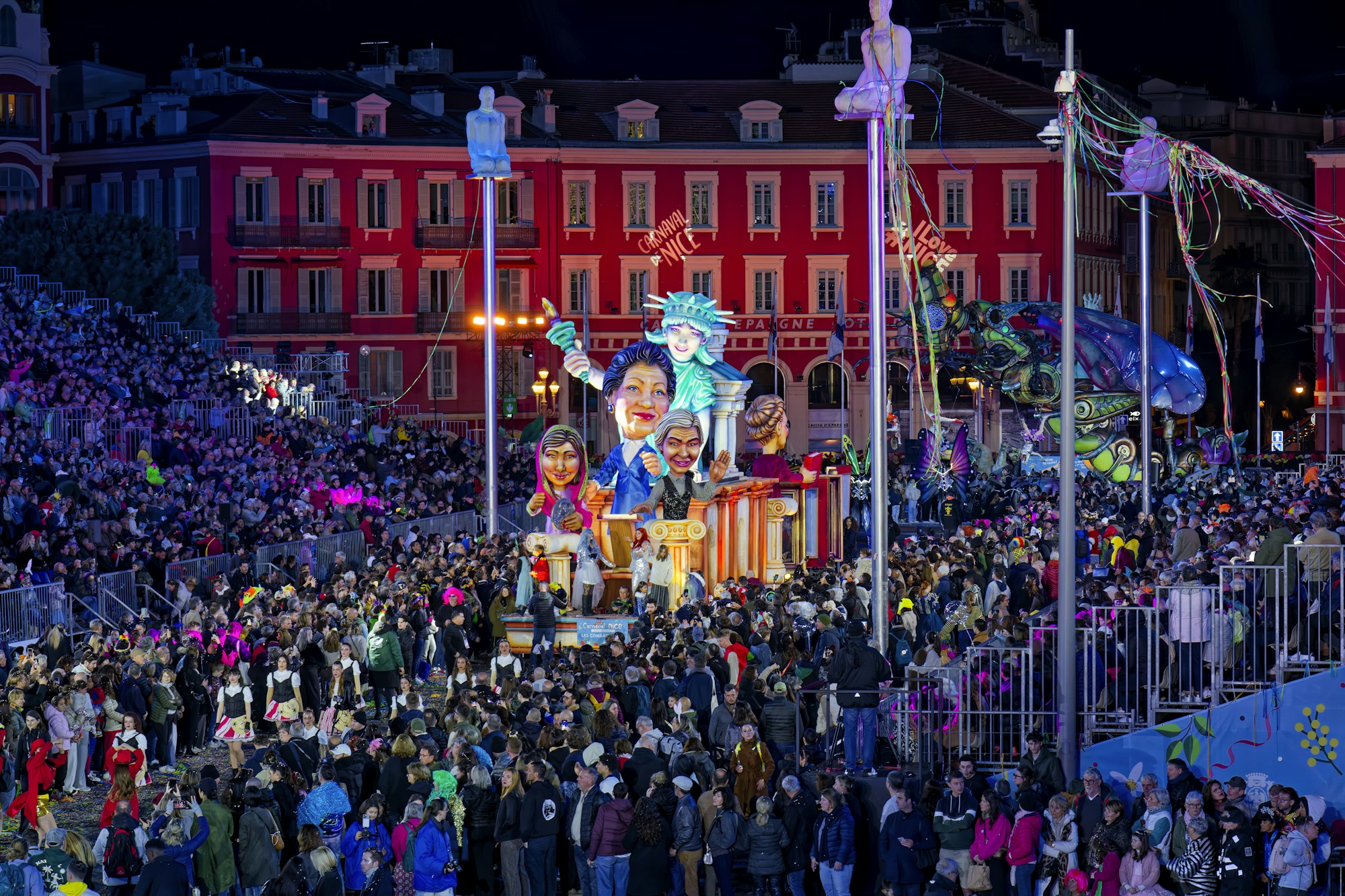 Illuminated floats and carnival masks passing a crowd of spectators at night in Nice