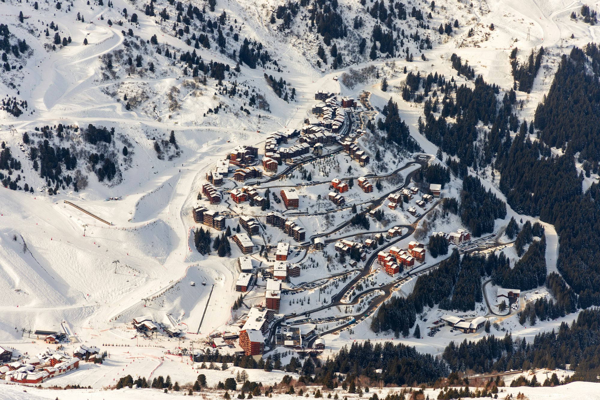 Villaggio alpino innevato visto dall'alto, con chalet e piste da sci