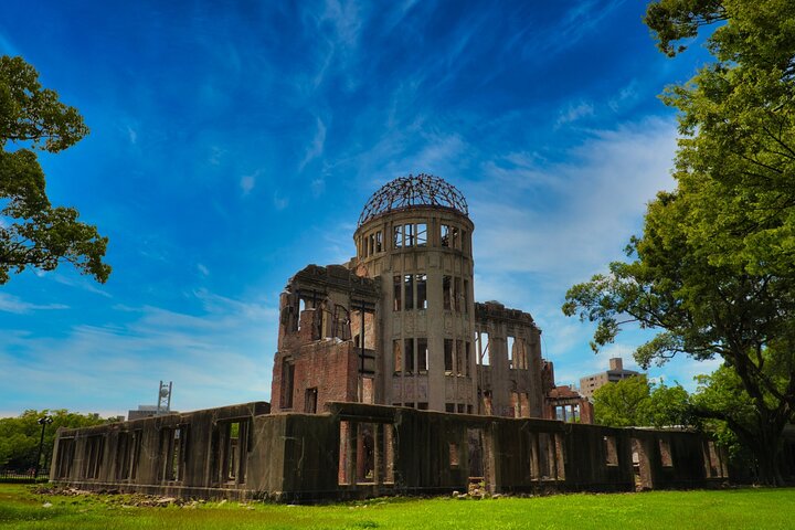 Groupe écoutant un guide local devant un monument commémoratif d'Hiroshima