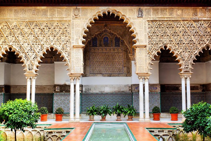 Kleingruppe hört ihrem Guide in einem Patio des Alcázar zu