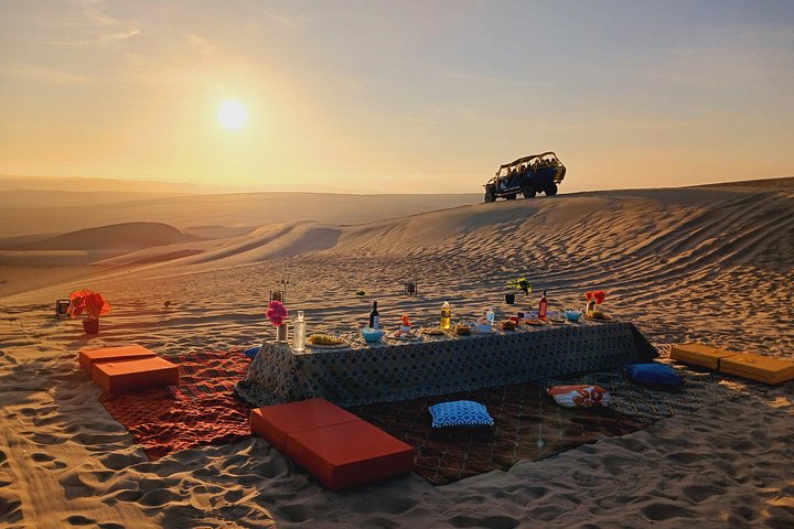 Picnic table set up in the desert at sunset near Huacachina