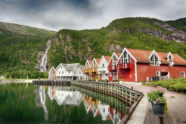 Wooden village on a fjord shore, waterfall down the cliff