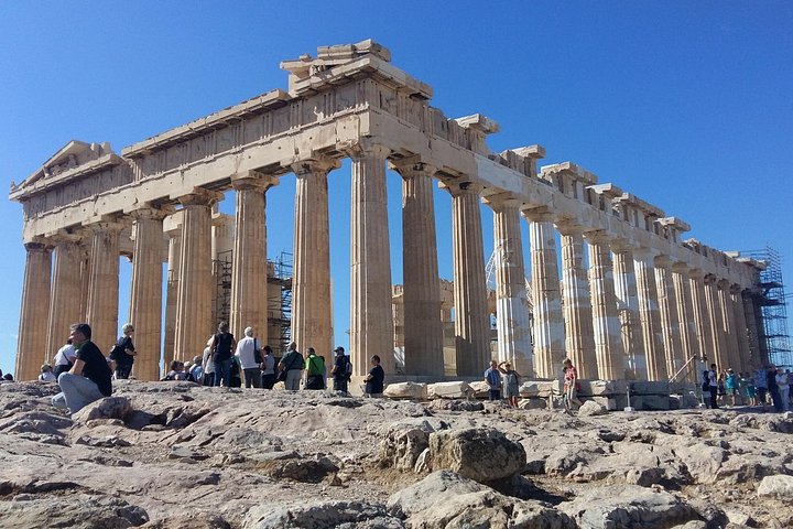 Petit groupe écoutant un guide près des monuments de l'Acropole