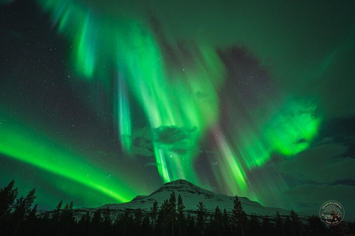 Auroras boreales verdes sobre una montaña nevada