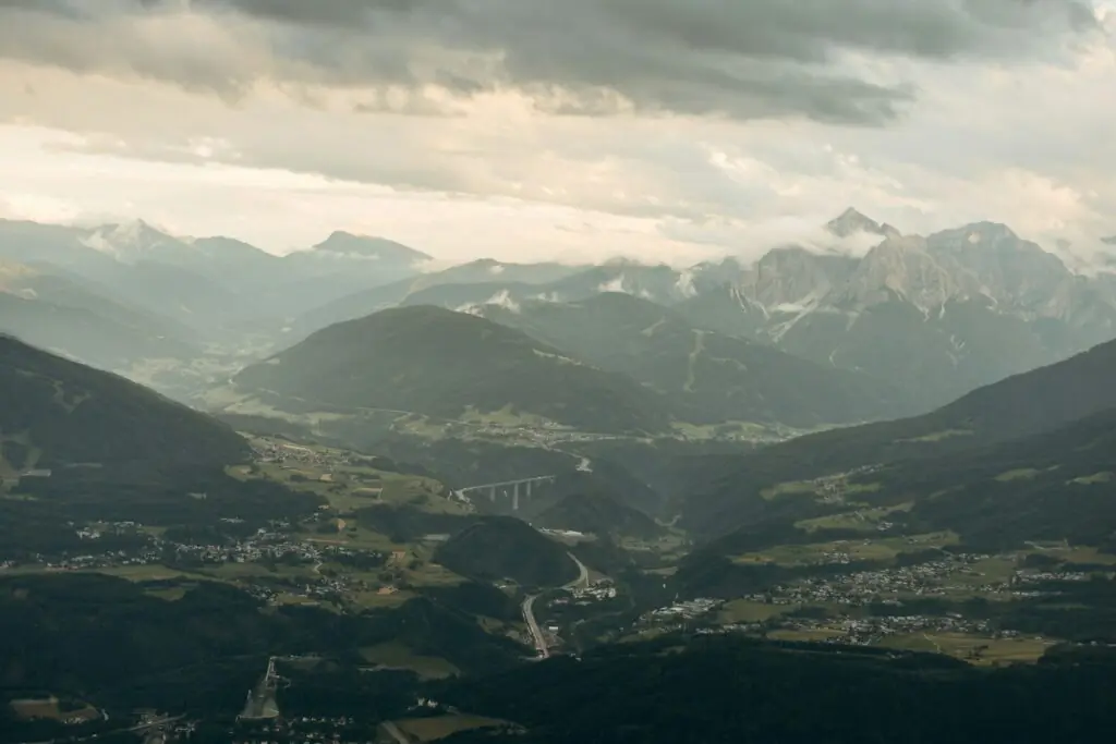 Vallée de montagne avec une route qui traverse le paysage sous un ciel nuageux