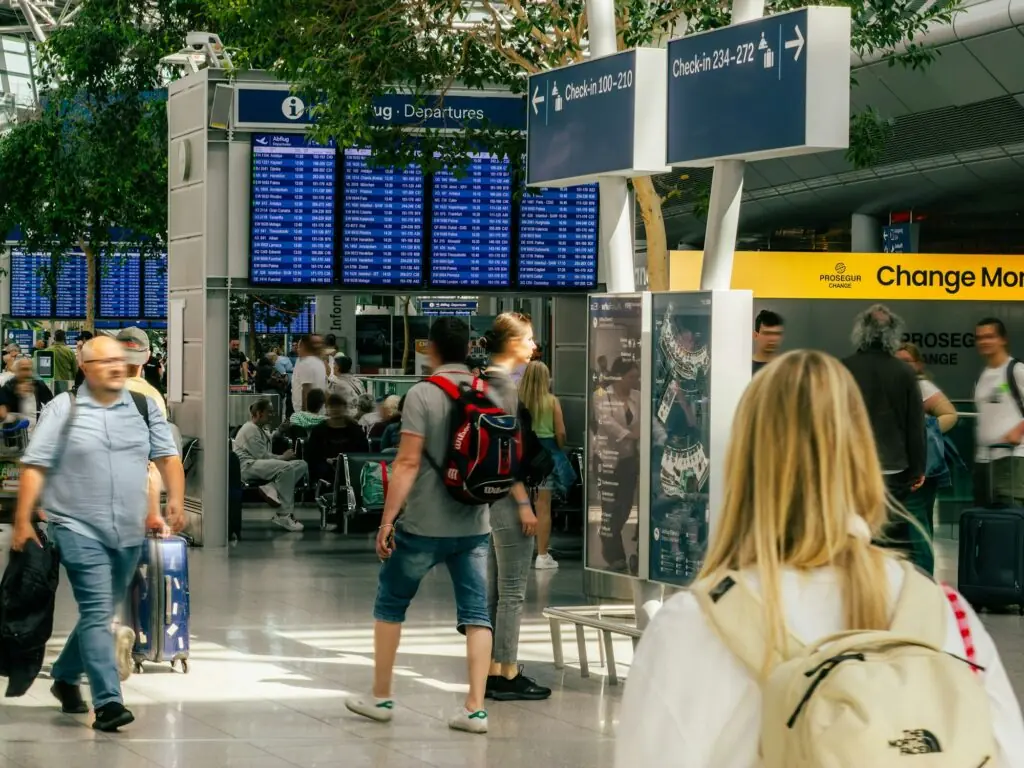 Voyageurs dans le hall des départs d'un aéroport devant le tableau des vols